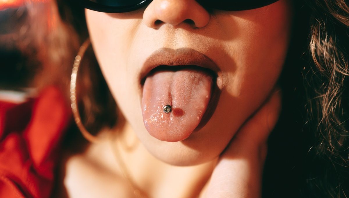 Primer plano de una lengua con piercing de barra metálica