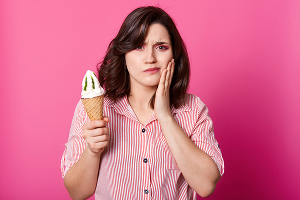 Mujer con molestias de sensibilidad dental luego de comer un helado